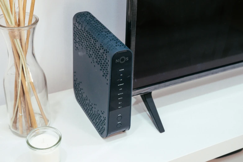 a tv sitting on top of a shelf near a vase with flowers