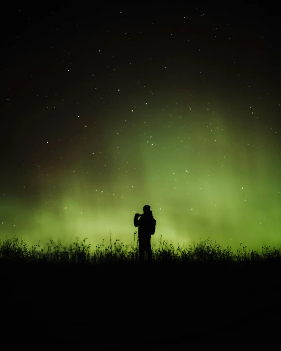 a man standing in a field with an astronomy sky above him