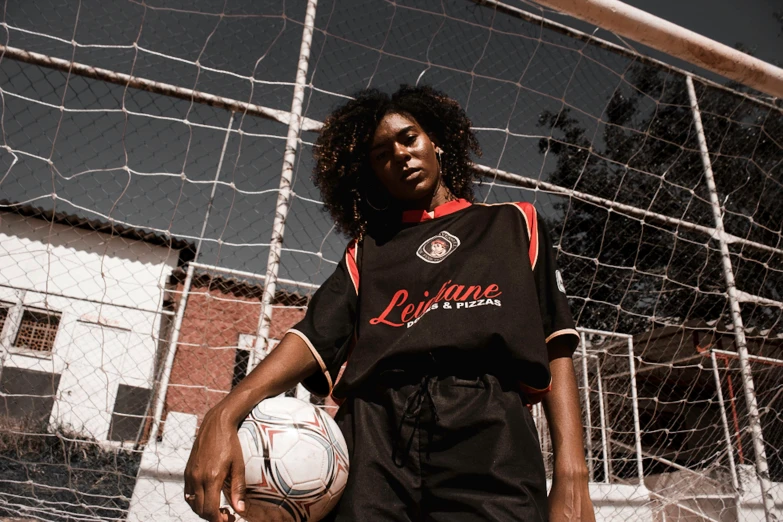 a women is holding a soccer ball behind a net