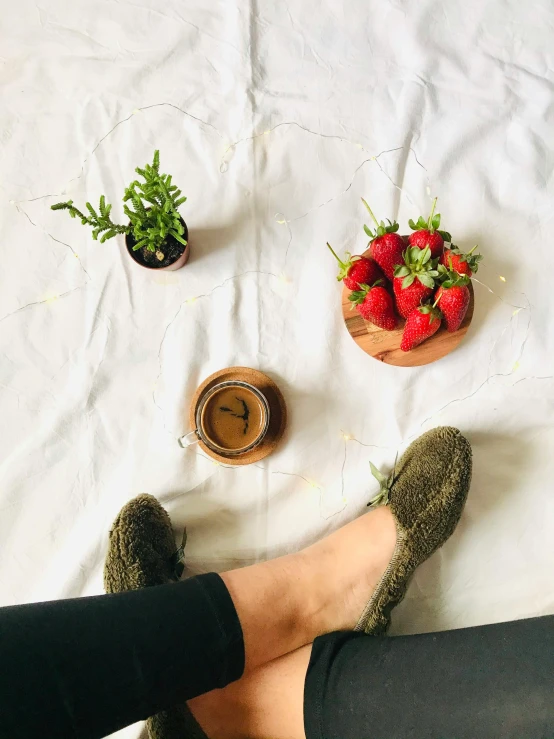 a person is sitting in front of some strawberries and coffee