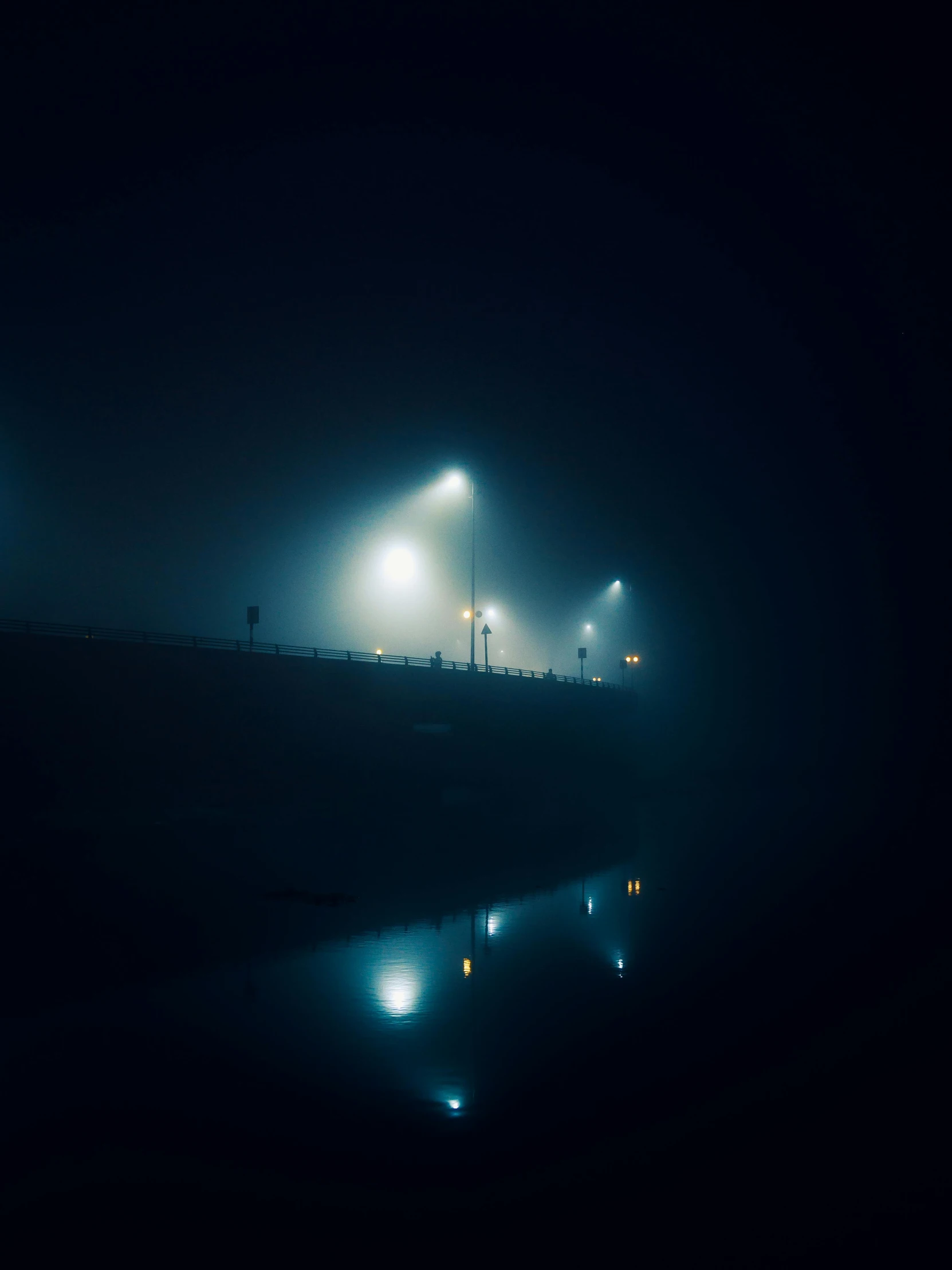 street lights at night with fog and reflective water in the foreground