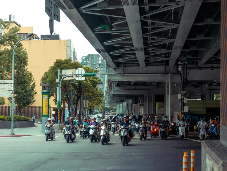 a large group of motorcyclists drive under an overpass