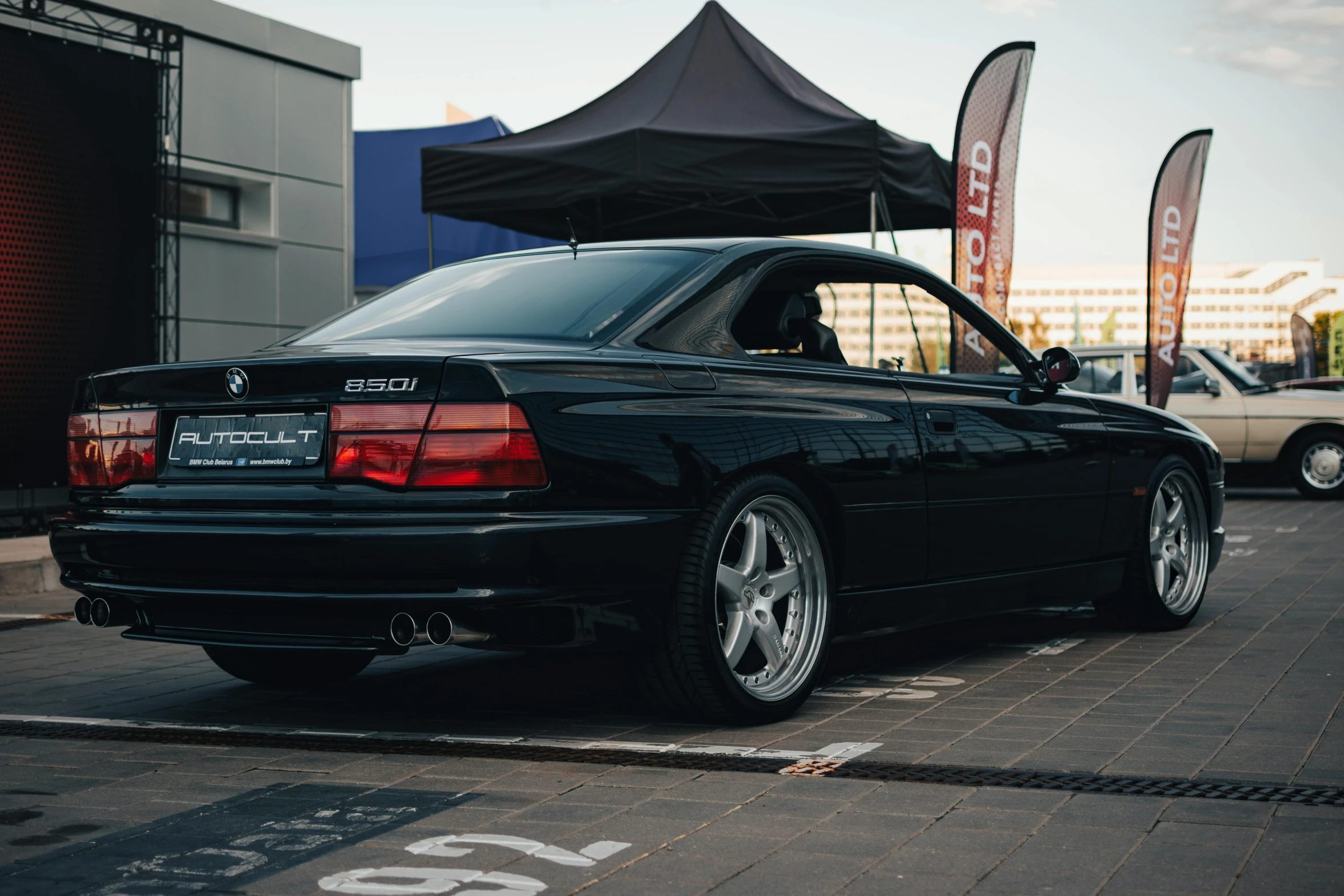 the bmw e36 is parked on a sidewalk