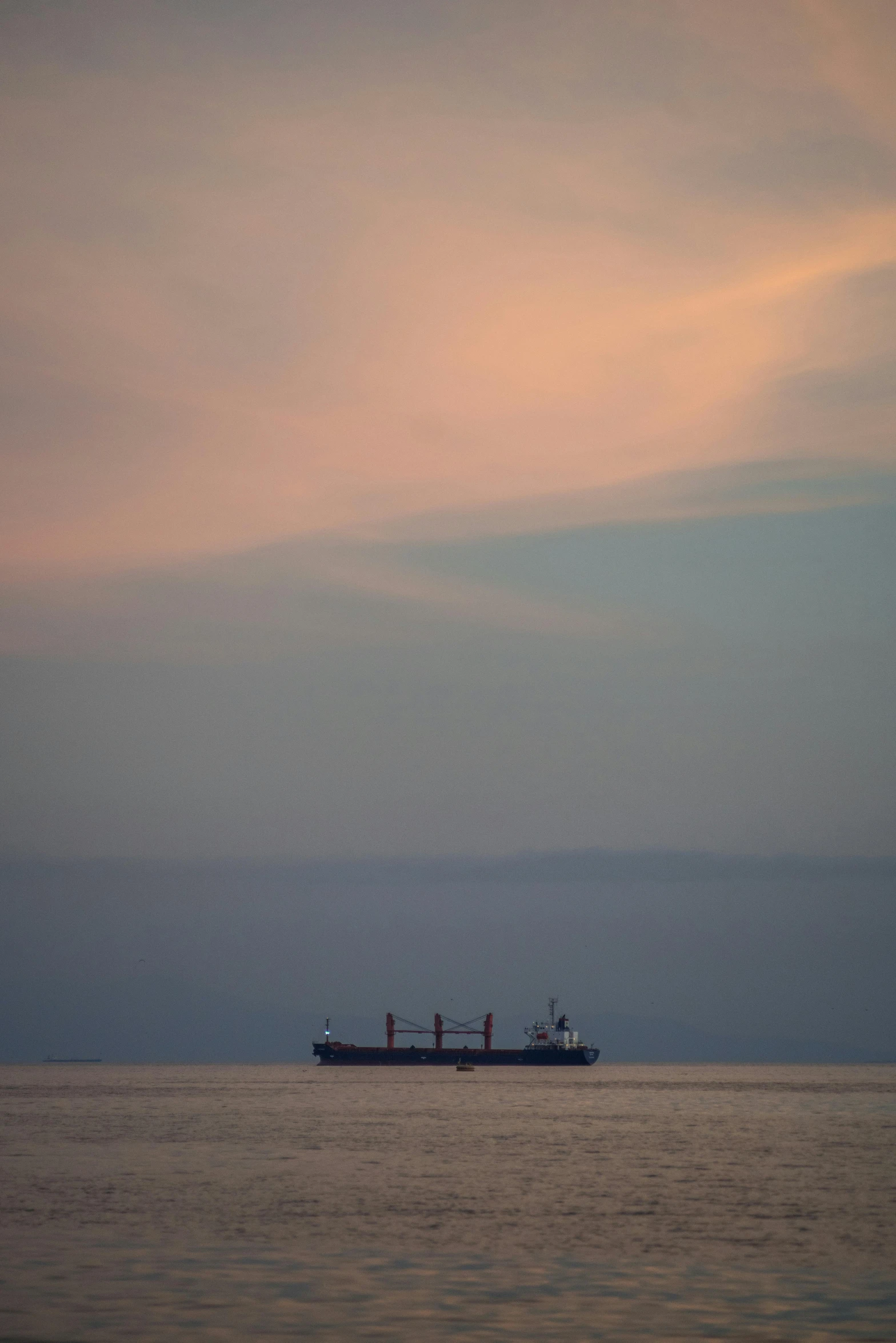 an orange and gray sky above a ship in the ocean