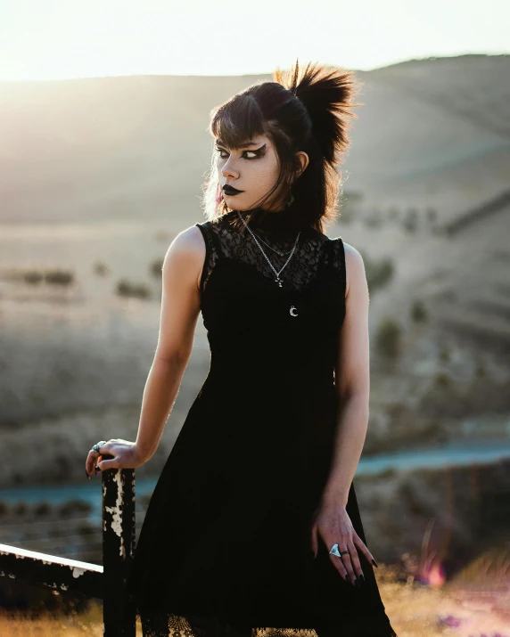 a woman is standing in a field holding a black umbrella