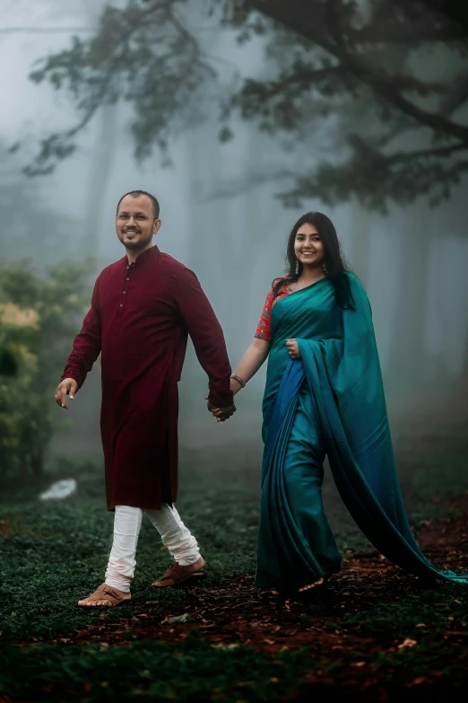 a couple is walking in the woods holding hands