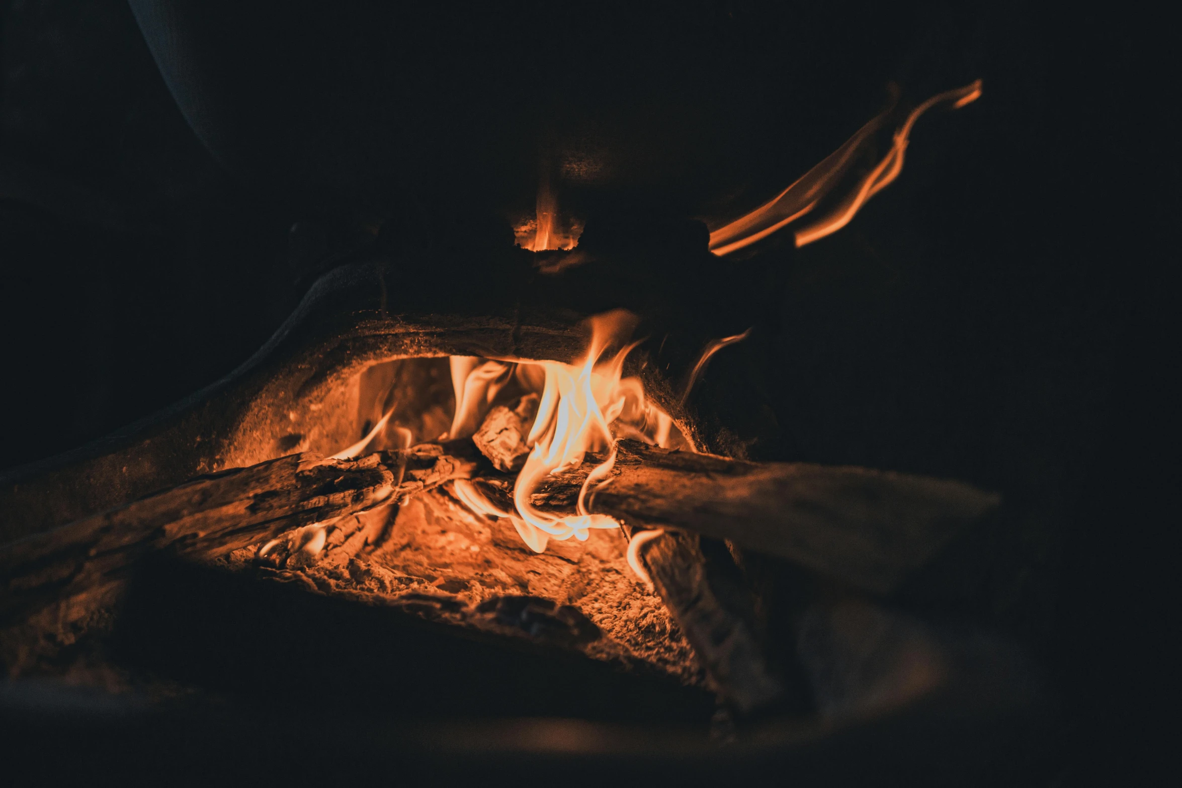 someone is laying next to an open wood fire