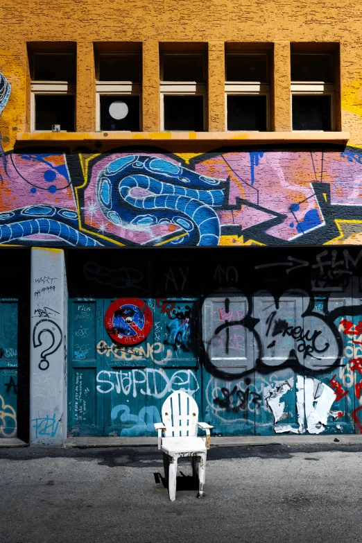 a chair that is on the sidewalk by some graffiti