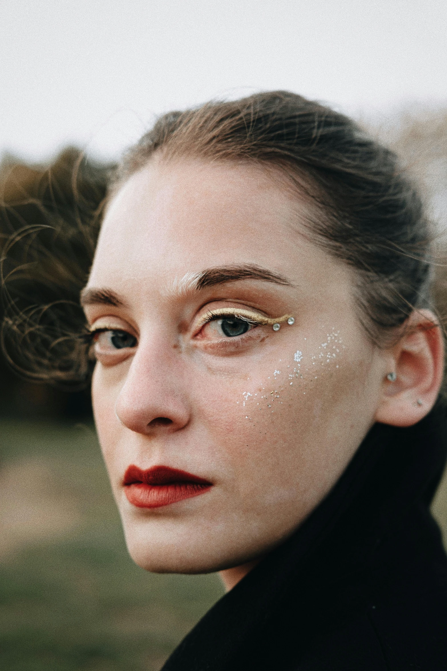 a woman with brown eyes and white makeup looking to the side