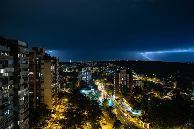 lightning in a city at night with buildings and trees