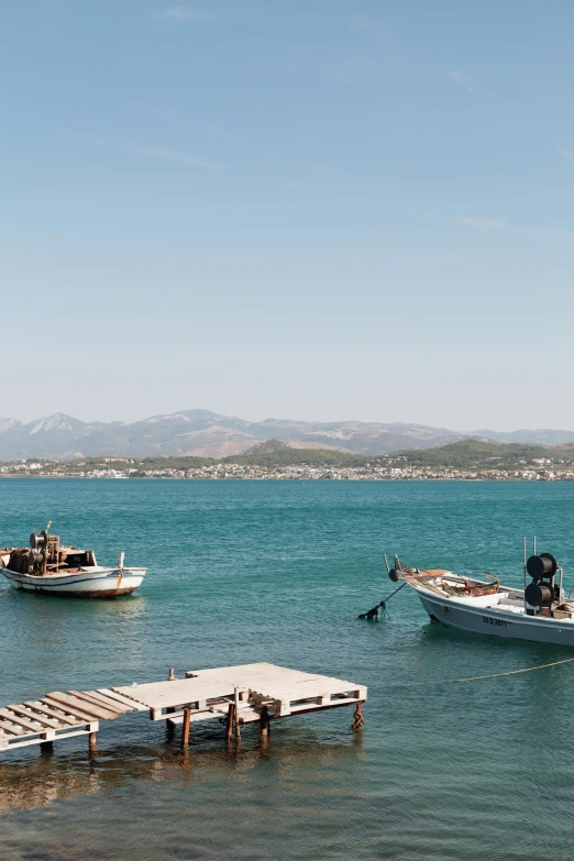 two boats are anchored near a small dock