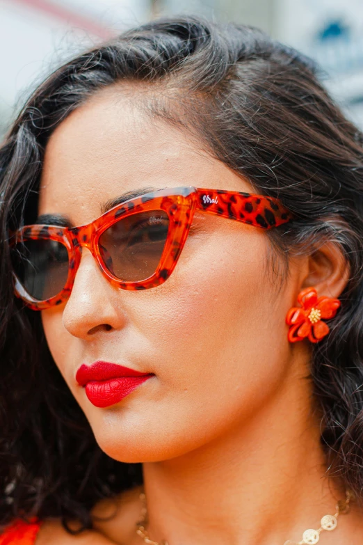 the young woman in sunglasses is wearing a red flower necklace