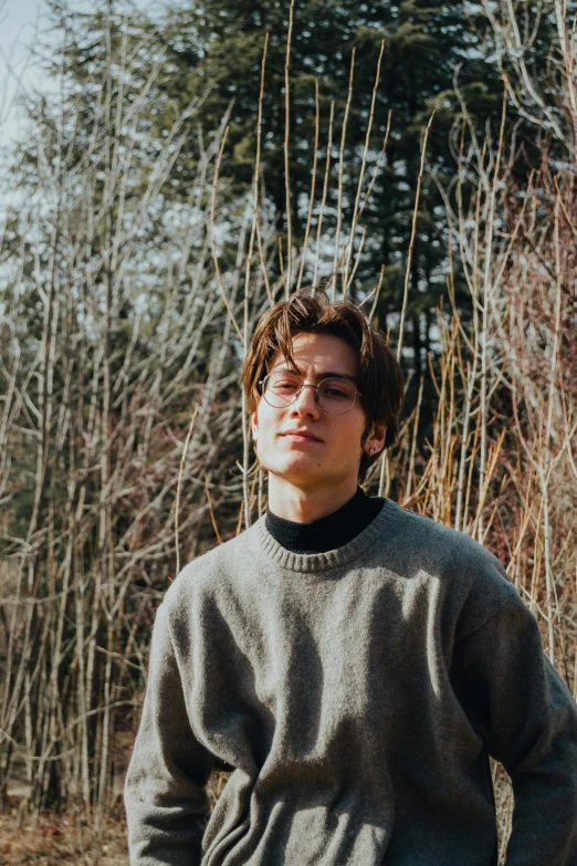 the young man is wearing glasses and a sweater