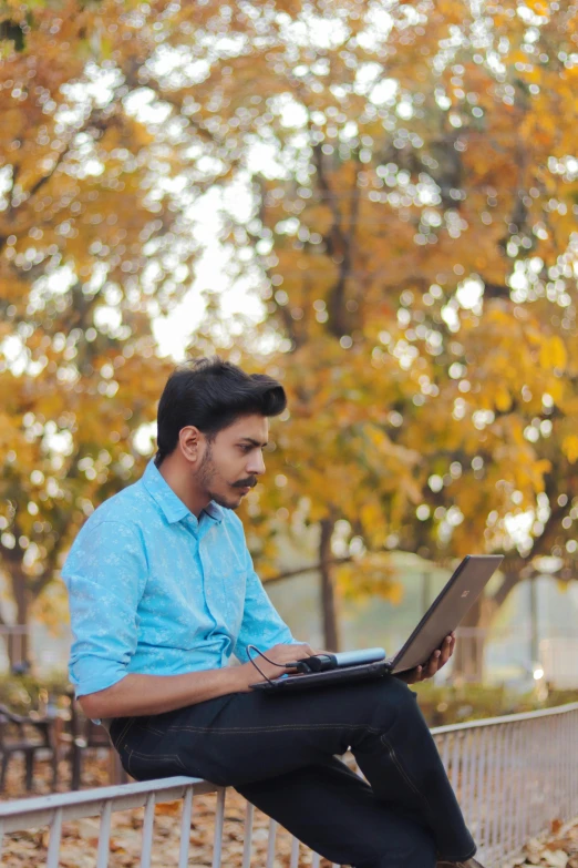 a man is using a laptop sitting on a ledge