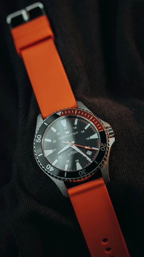 an orange watch with an emblem on it