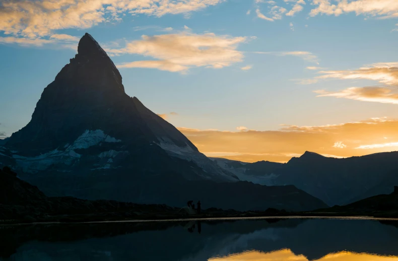 a silhouette of two people looking at the mountains