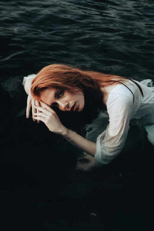 a young red headed woman in the water wearing a dress