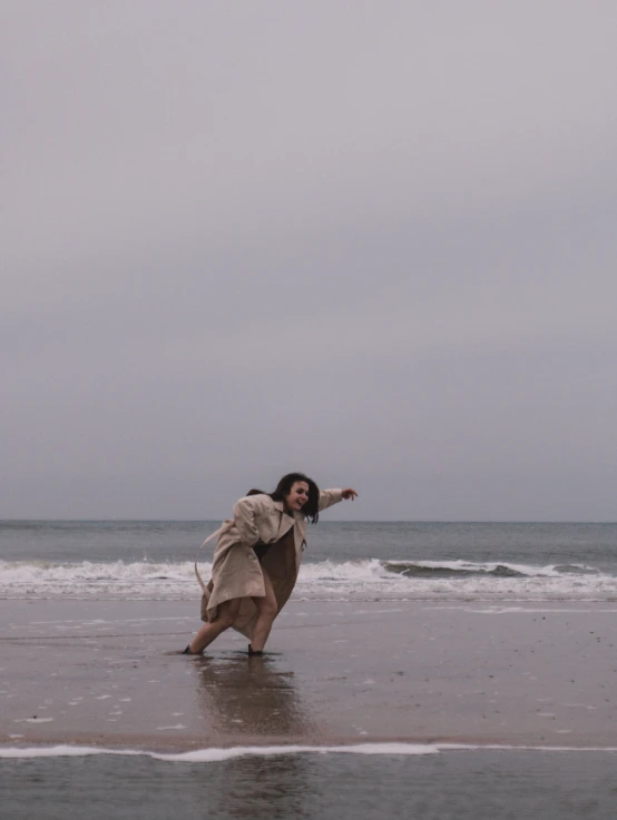 a woman standing on a wet beach holding a kite