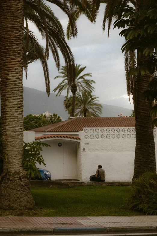 the man is sitting outside by his house