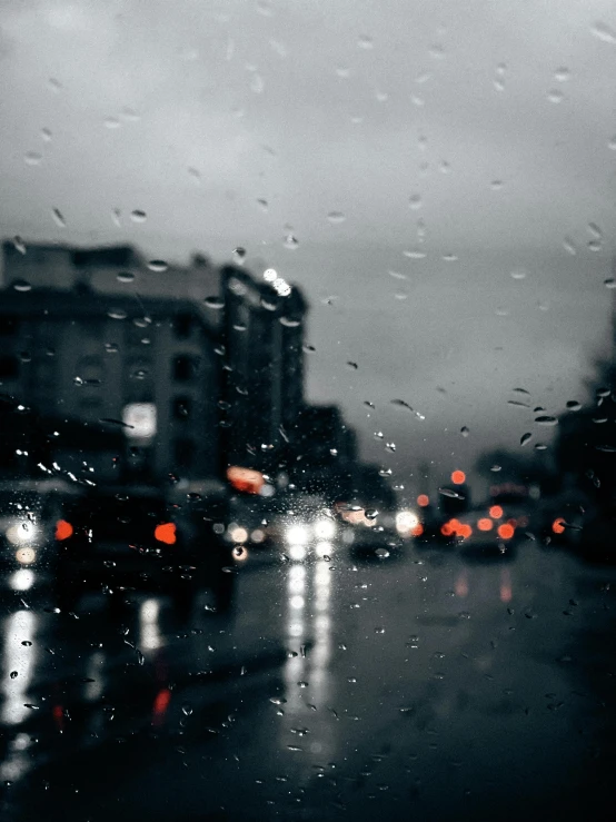 a view outside of a window, through the windshield and onto a street at night