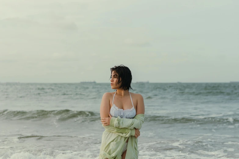 a woman standing on a beach while looking into the ocean