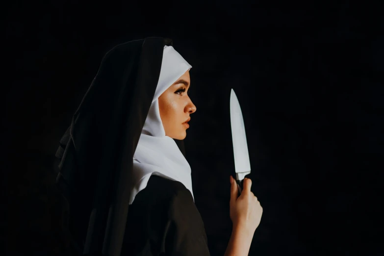 a nun holding two knives in the dark