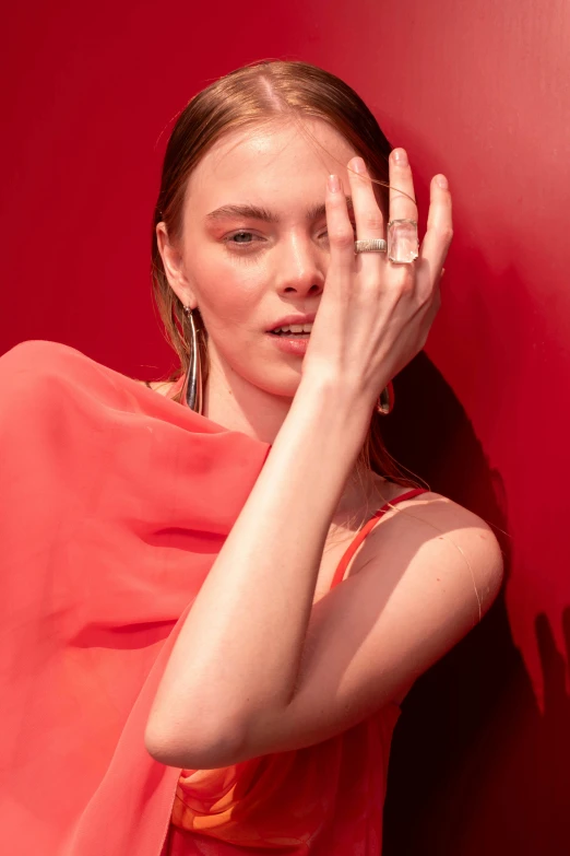 woman covering her face and touching hands with red wall background