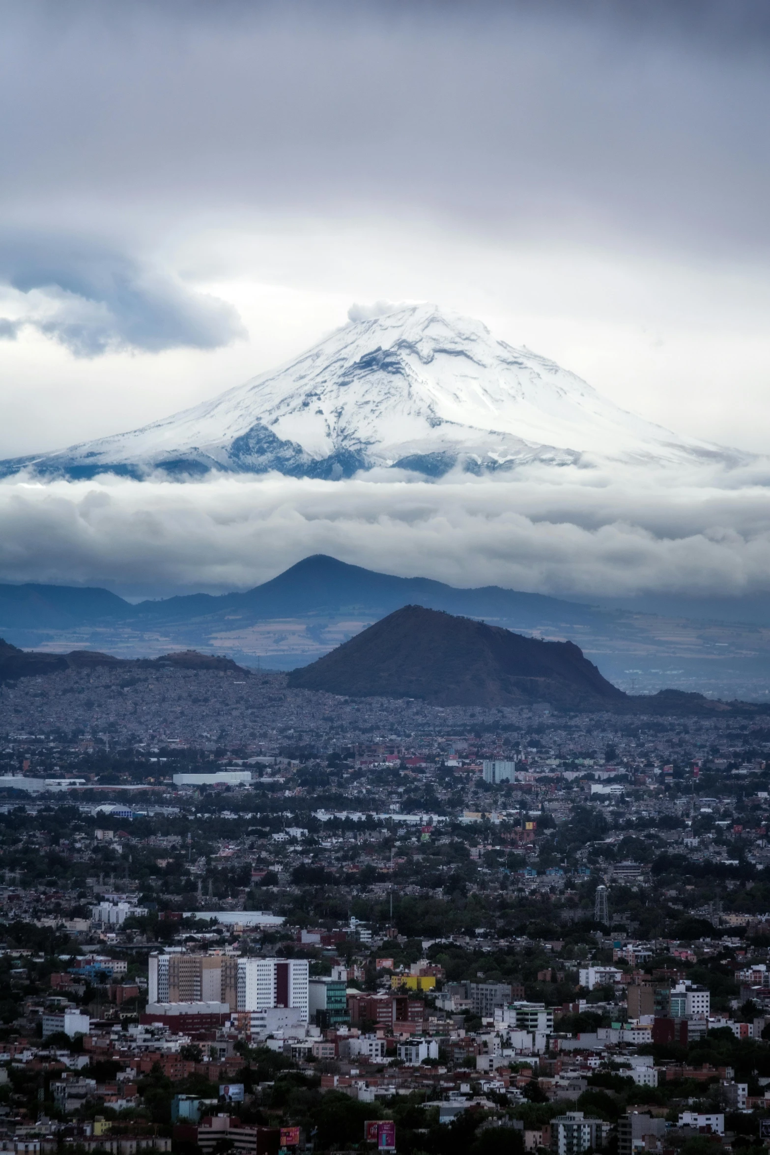 a large white snow covered mountain rising above the city