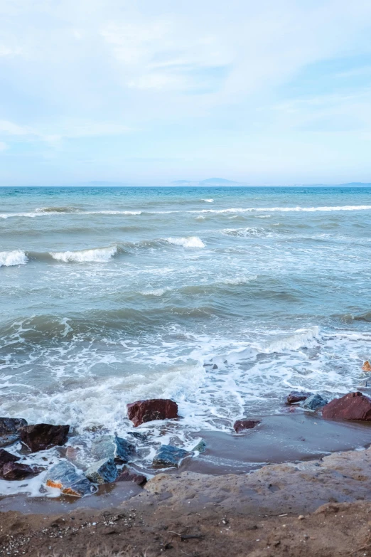 an ocean view of water and rocks on the beach