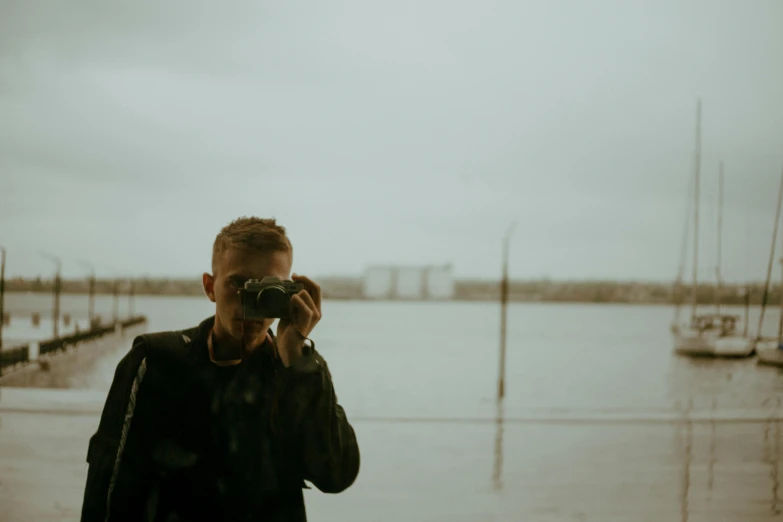 the man is taking a picture of the water and boats