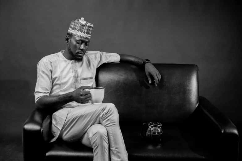 a man wearing a crown sitting on a black couch