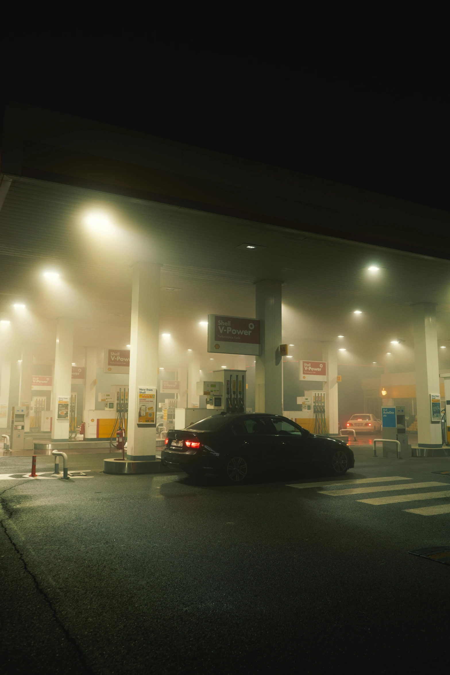 two cars stopped at an empty gas station