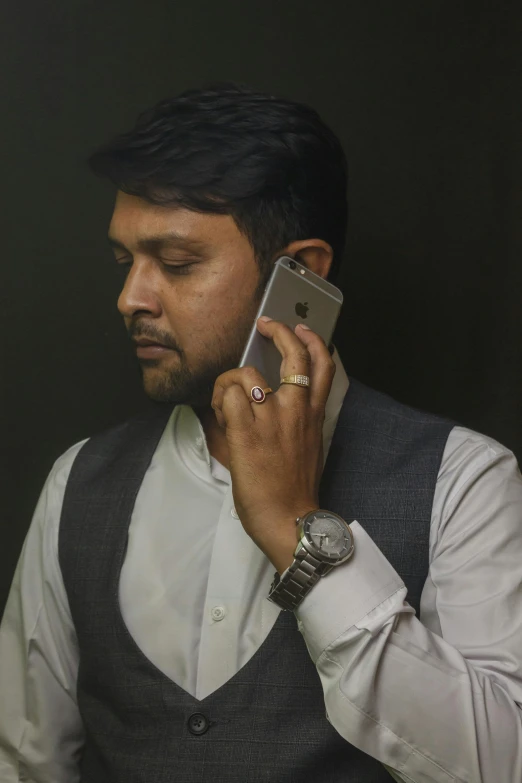 a man with a gray vest talking on a cell phone