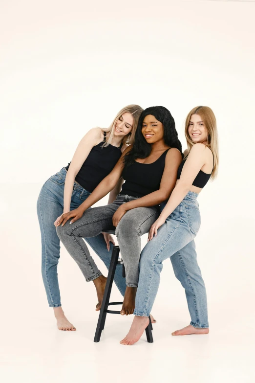 three women in black shirts posing on a stool