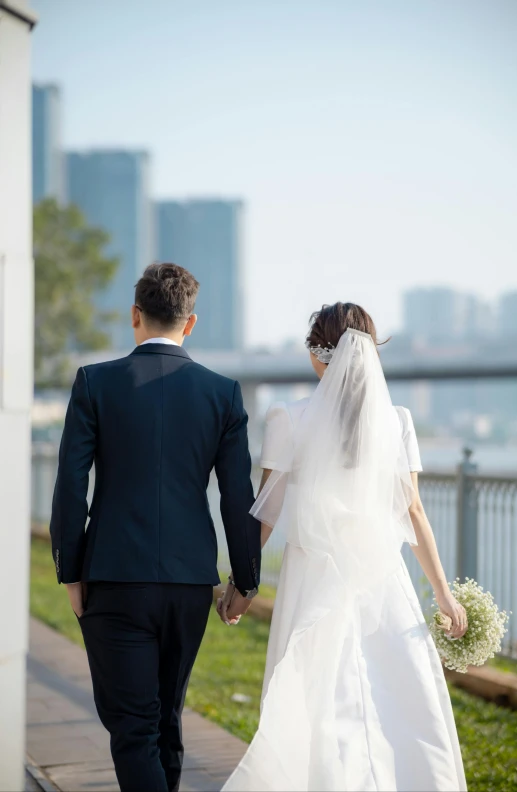 a bride and groom walking on the sidewalk