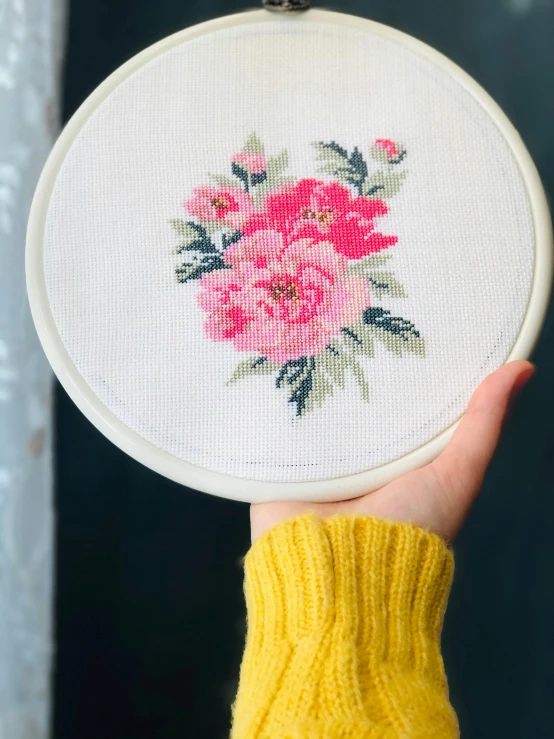 someone holding a floral embroidered object to show it off