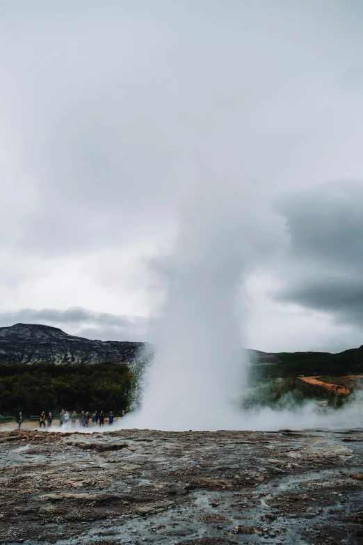 a group of people standing near a geyser