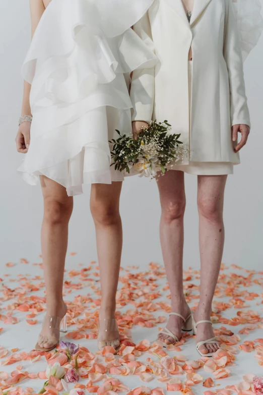 two models in white dresses surrounded by rose petals