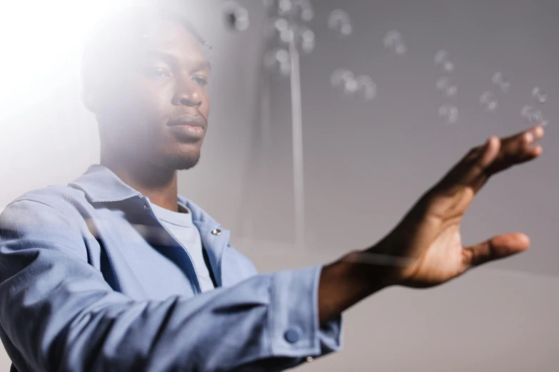 a man holding out his hands with soap bubbles floating from it