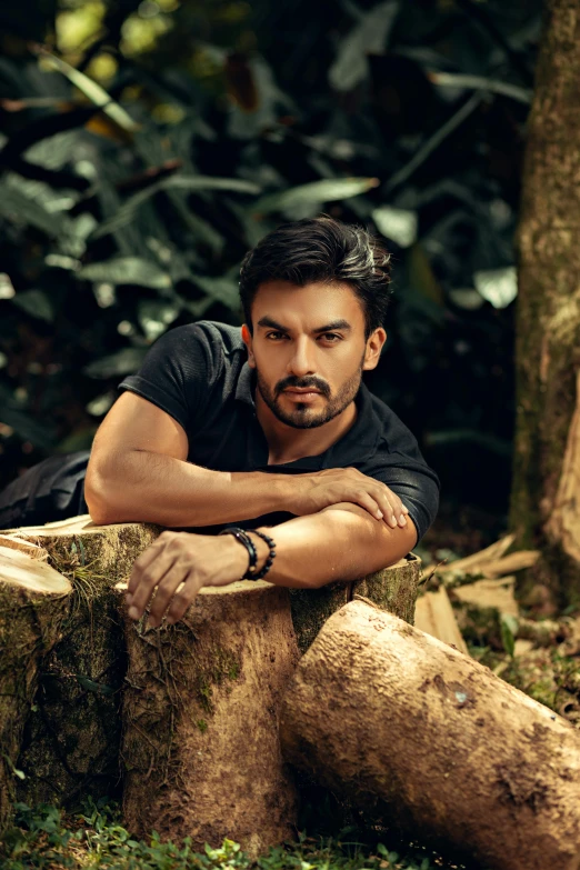 a man leaning on a log in the woods