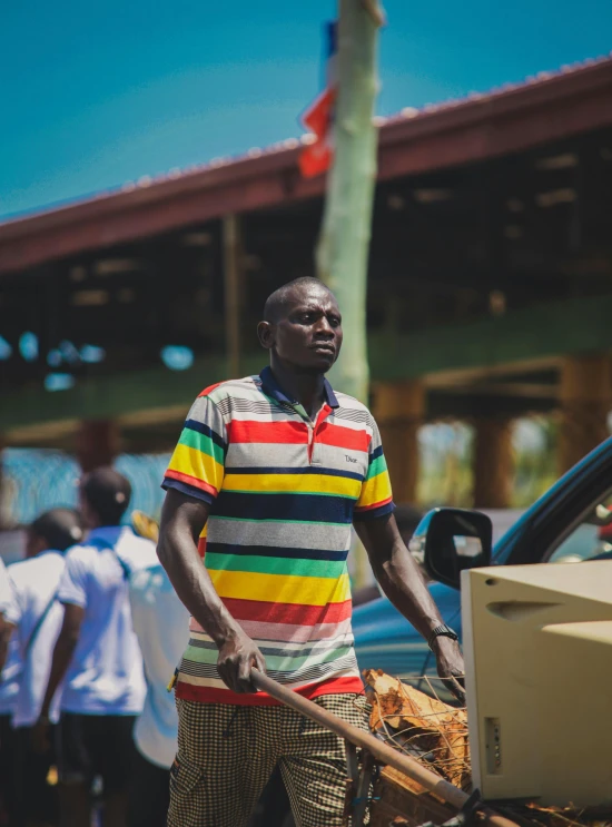 man wearing striped shirt and holding wooden instrument in hand