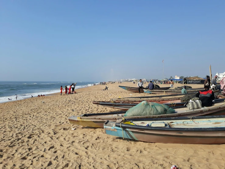 many boats sitting on a sandy shore near the ocean