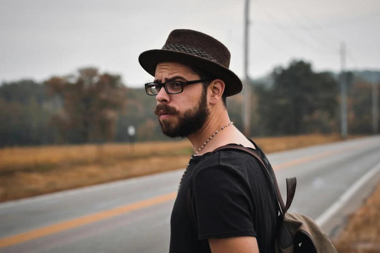 a man with a hat and glasses looking off into the distance