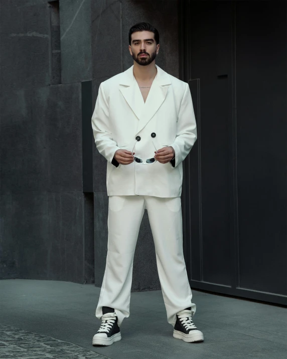 a male model in a white suit and tennis shoes