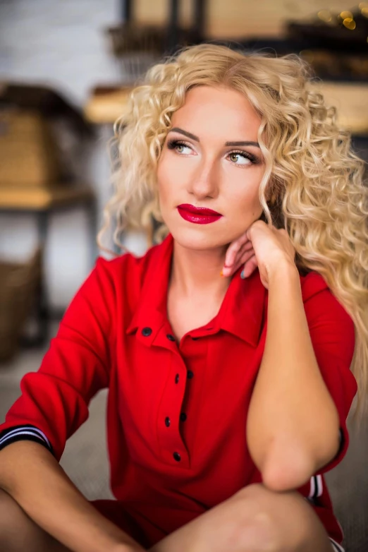 blond woman wearing a red shirt posing for a po