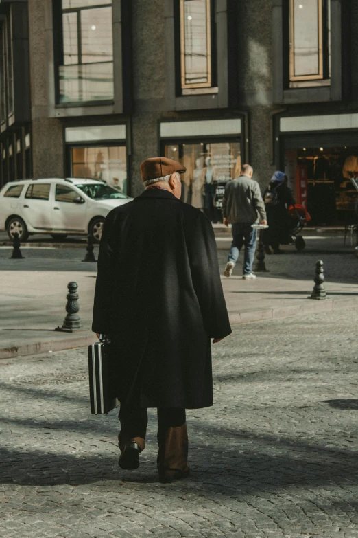 man in business coat with suitcase walking past buildings