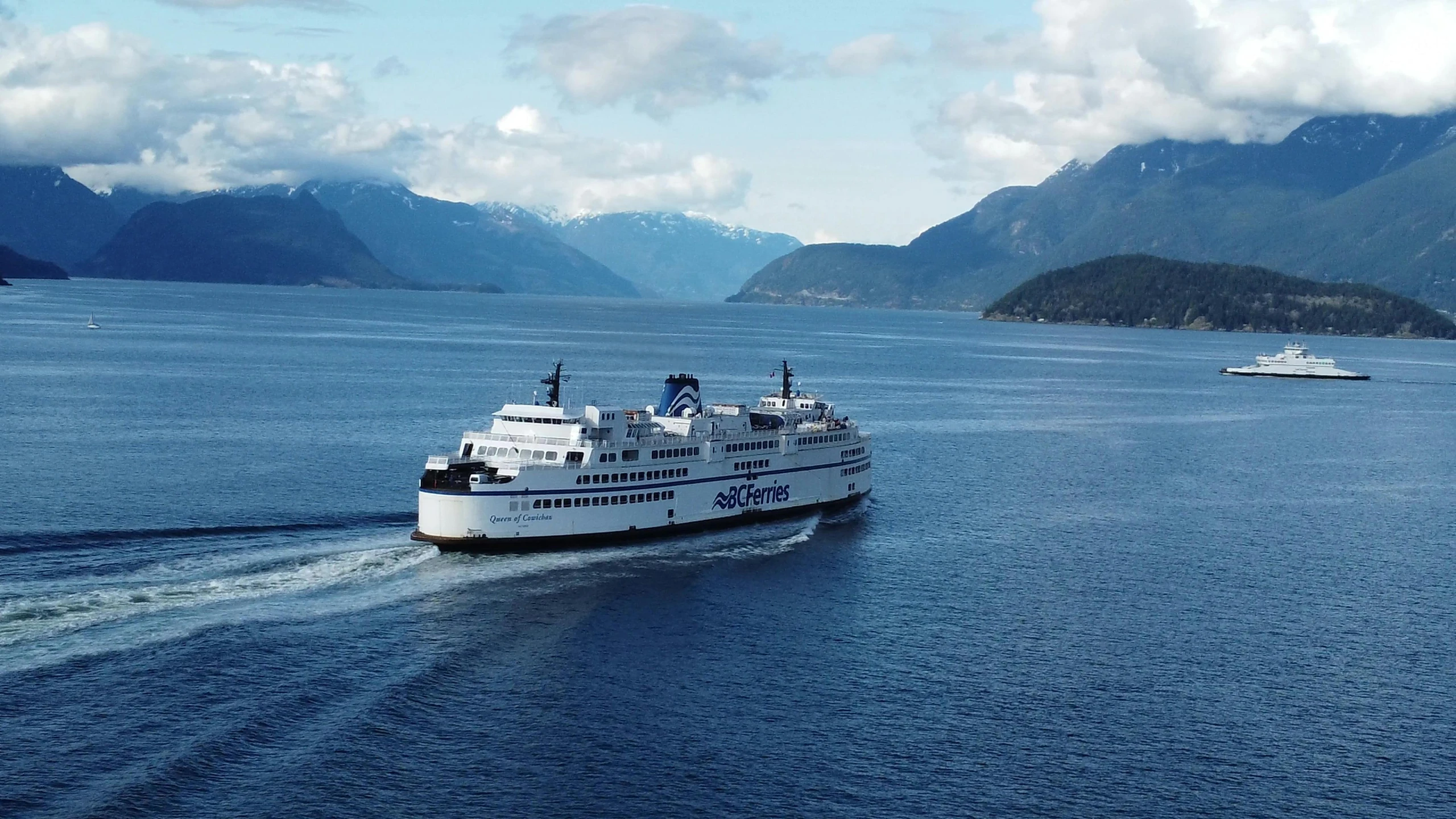 the ferry is driving along the water by mountains