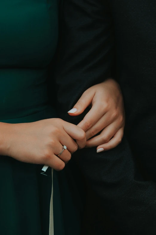 couple emcing each other while holding their engagement ring