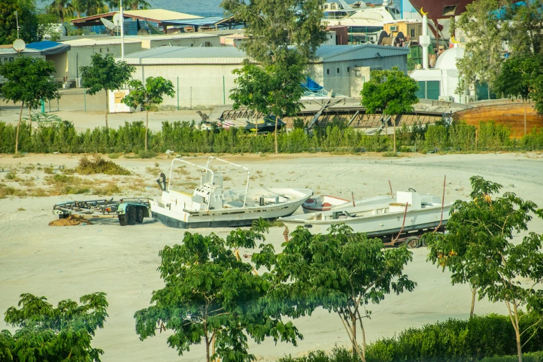 boats and vehicles in a parking lot next to some trees