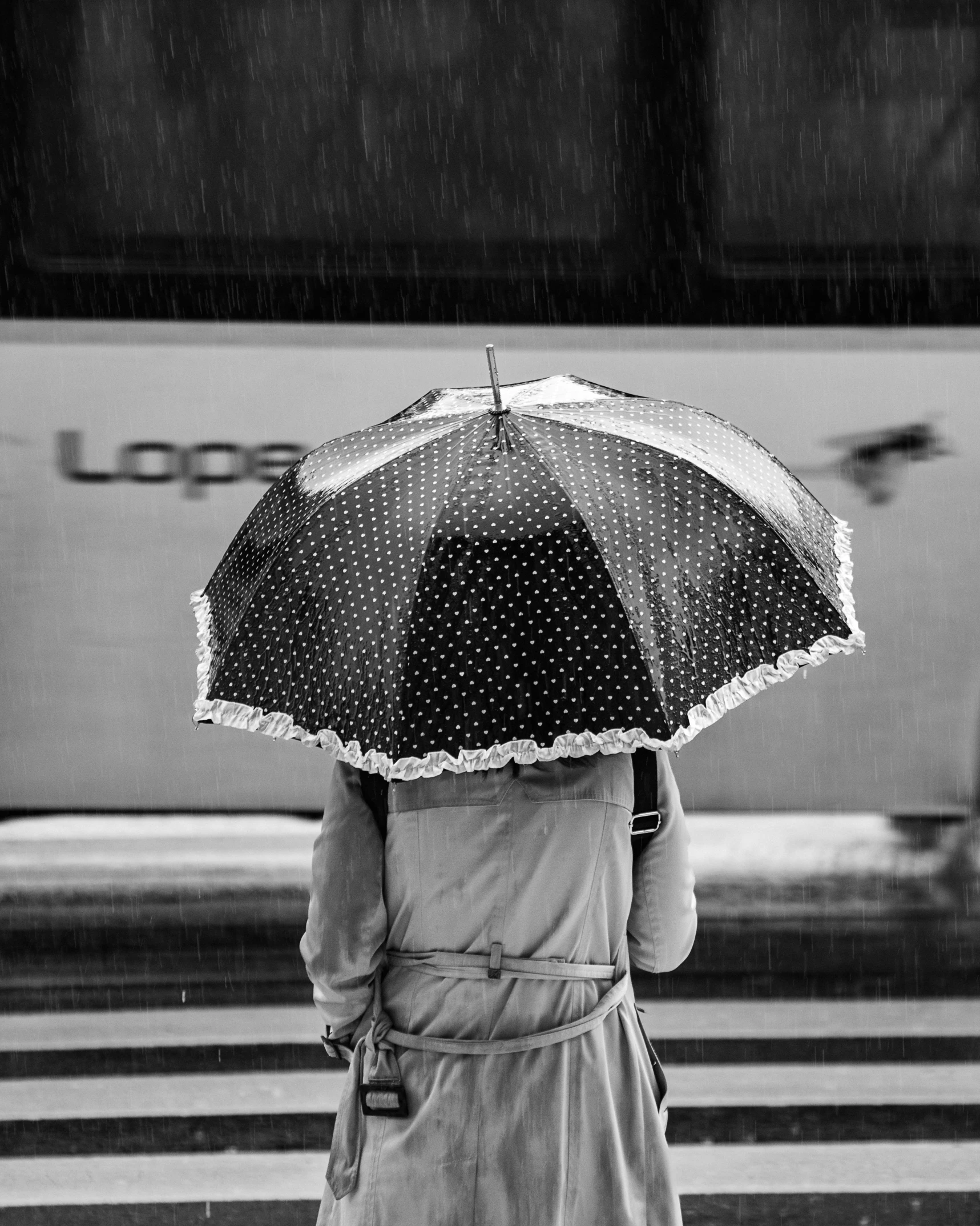 a woman with an umbrella waiting for the train